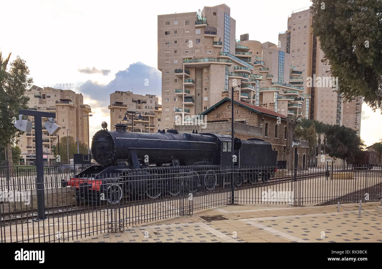 Une locomotive antique et la gare ferroviaire moderne entouré par des tours d'habitation à Beer Sheva en Israël Banque D'Images