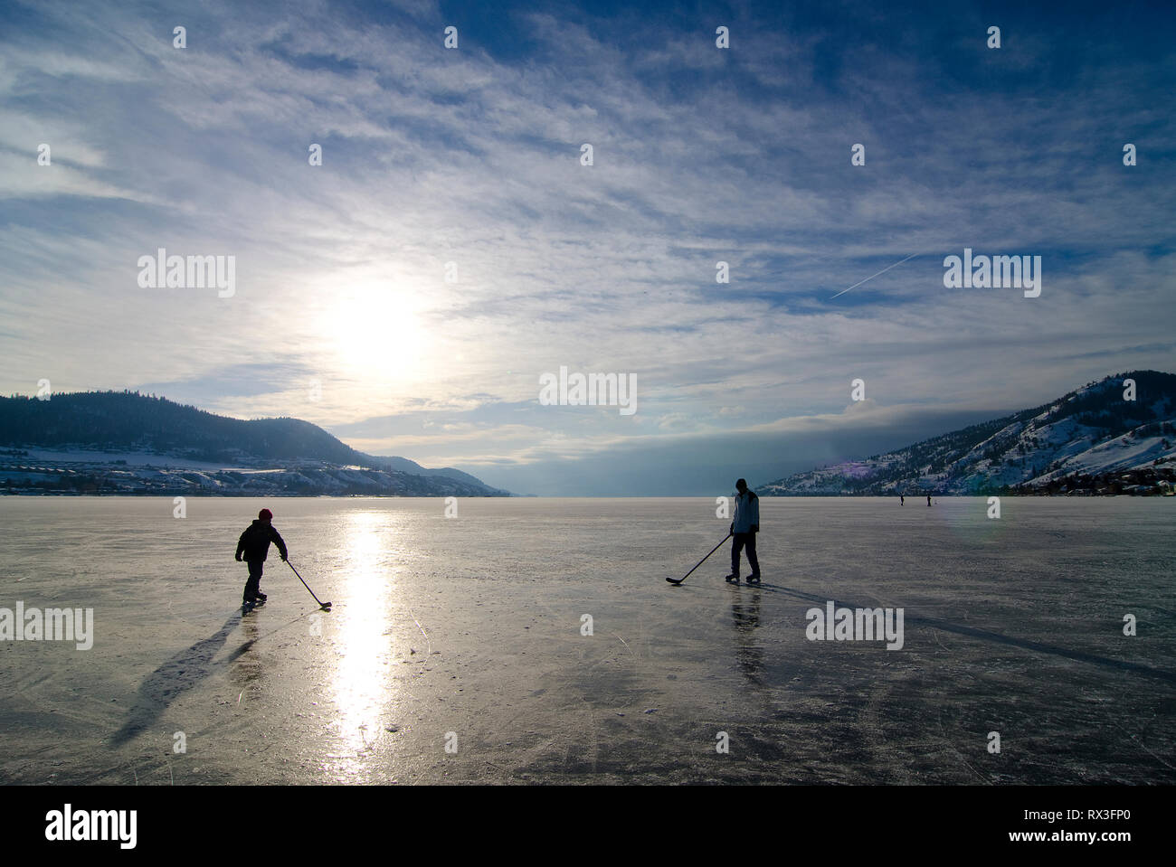 Deux personnes jouent au hockey sur la glace d'un lac Okanagan à Kin Beach à Vernon, Colombie-Britannique, Canada Banque D'Images