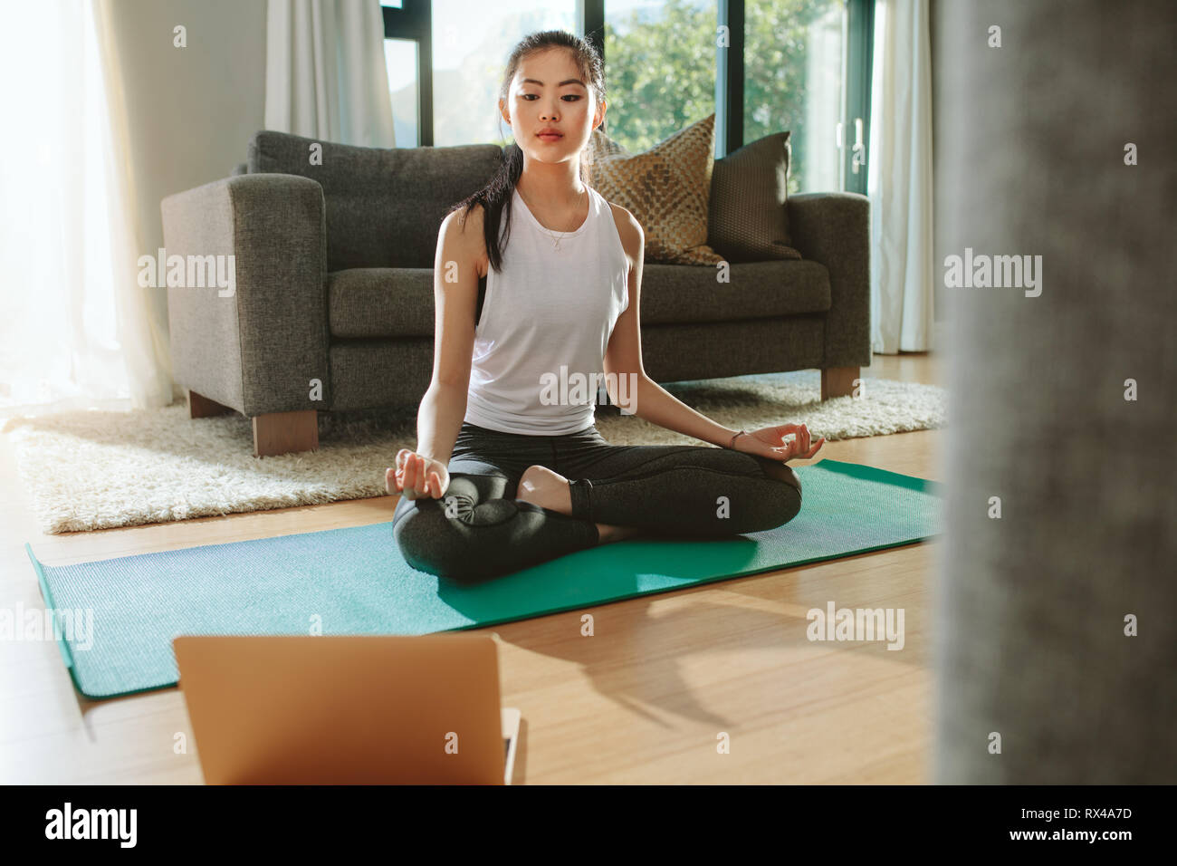 Fit woman doing yoga exercice tout en regardant tutoriel sur l'ordinateur portable à la maison. Belle femme chinoise exerçant sur une natte et regarder des vidéos d'enseignement Banque D'Images