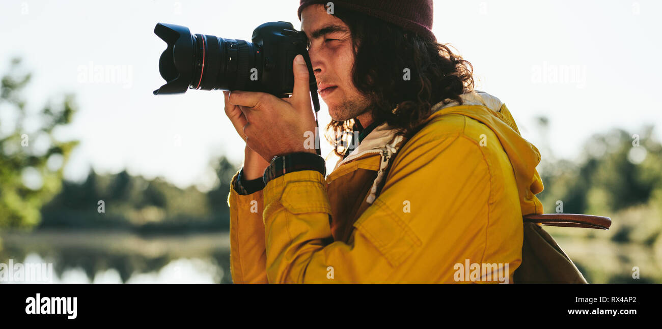 Portrait d'un homme prend une photo à l'aide d'un appareil photo numérique. Cropped shot d'un touriste à la recherche dans son appareil photo reflex numérique pour prendre une photo. Banque D'Images