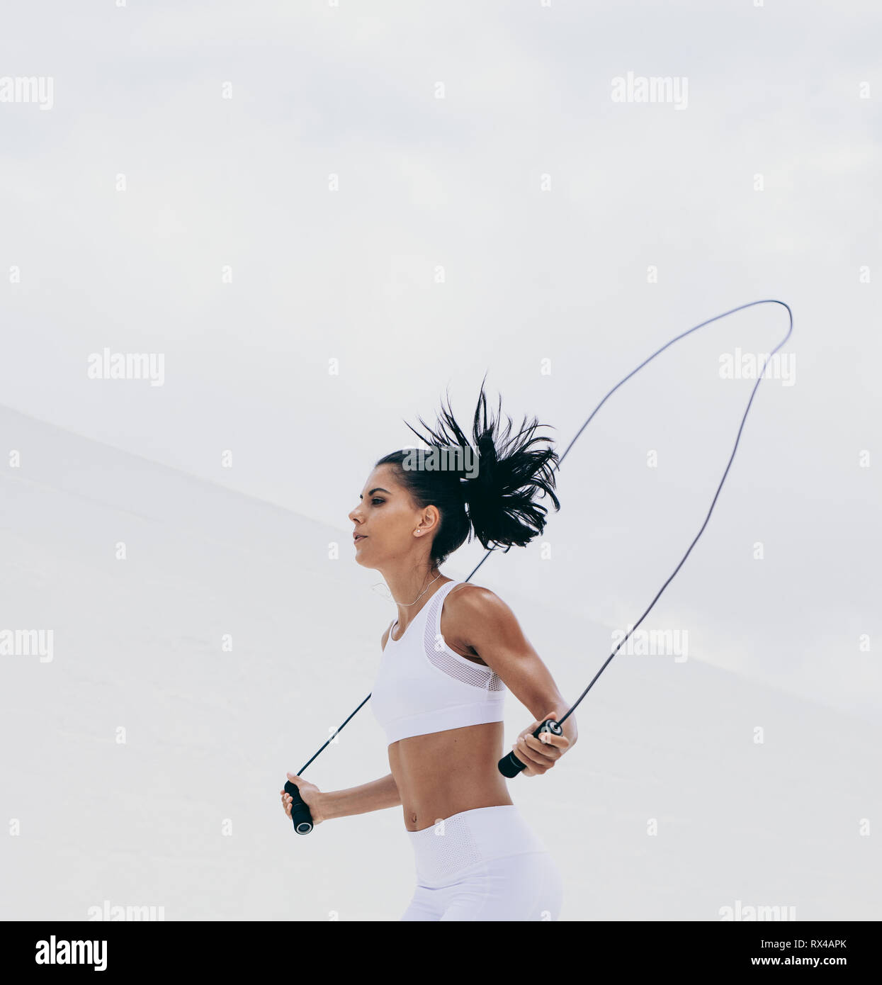 Cropped shot d'une athlète féminine en fitness porter l'élaboration avec une corde à sauter. Vue latérale d'une femme de remise en forme fitness training. Banque D'Images