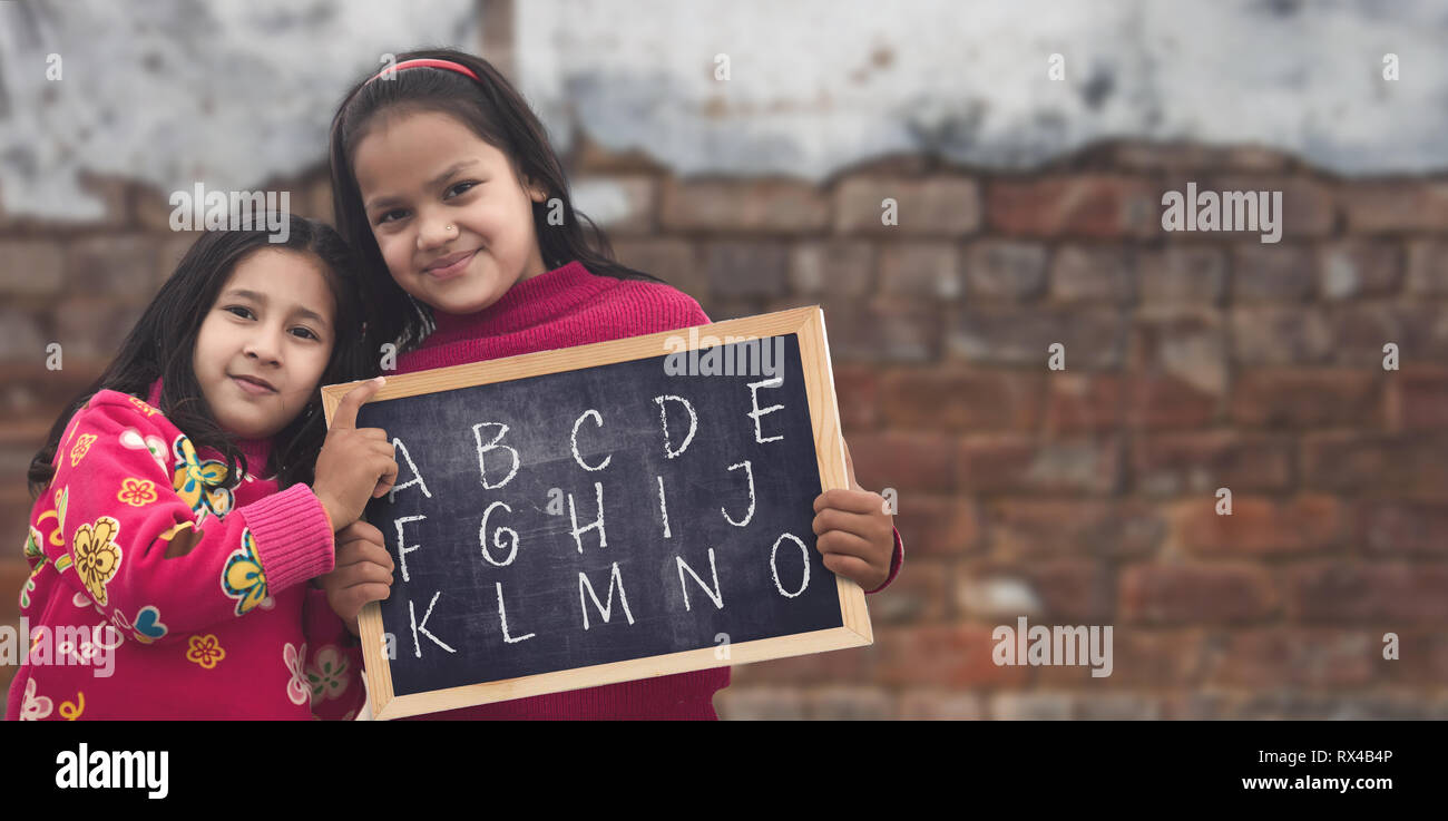 Adorable petit 6-8 ans et 8-10 ans filles indiennes, smiling holding abcd tableau. Banque D'Images