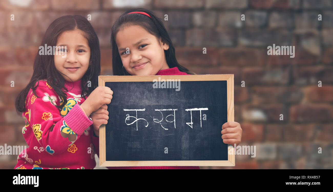 Adorable petit 6-8 ans et 8-10 ans filles indiennes, smiling holding Hindi alphabet tableau. Banque D'Images