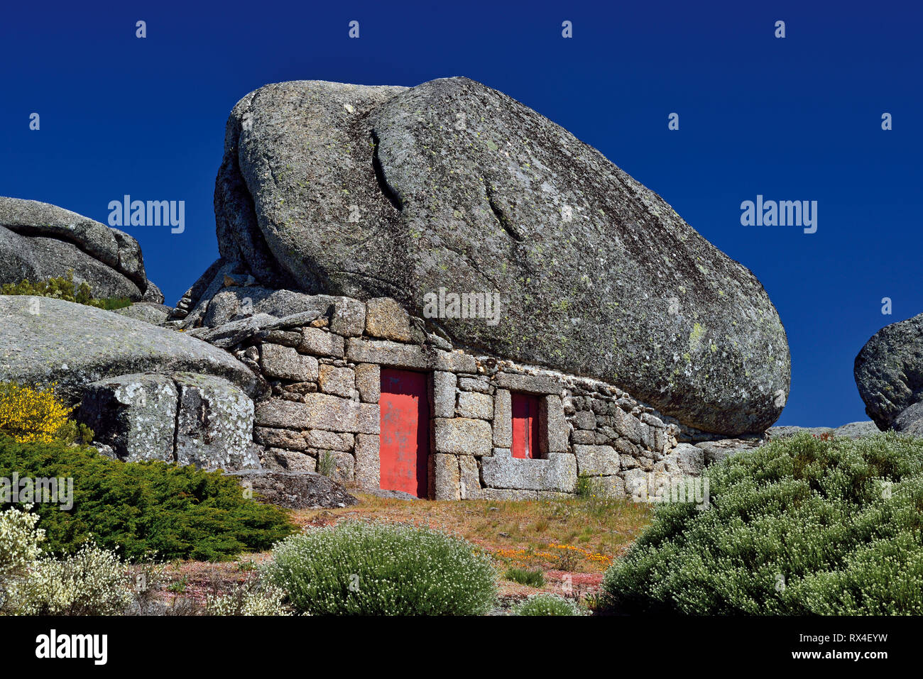 Maison en pierre de granit intégrée dans énorme rocher avec ciel bleu foncé sur une journée ensoleillée Banque D'Images