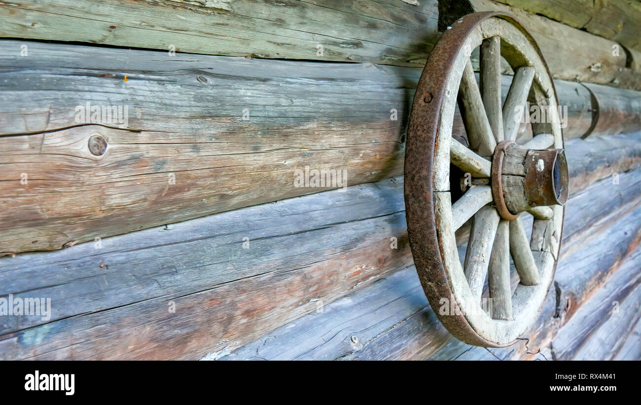 Une roue pendante sur la maison en bois rond. La roue est l'un des décors de la maison en bois rond Banque D'Images