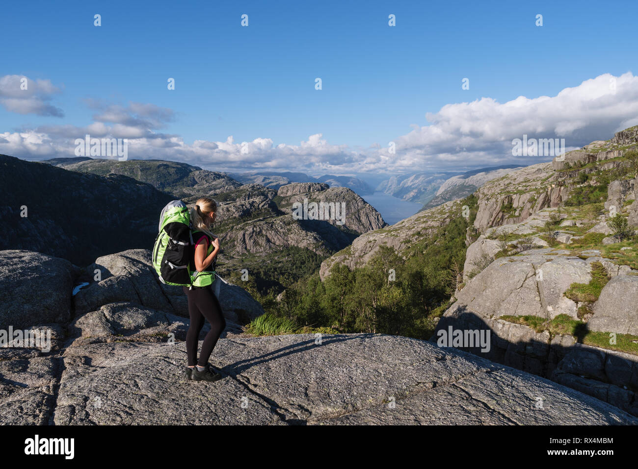 Touriste avec un sac à dos sur pathway Pulpit Rock. Fille blonde dans un trek en montagne. Avis de Lysefjord, Norvège Banque D'Images