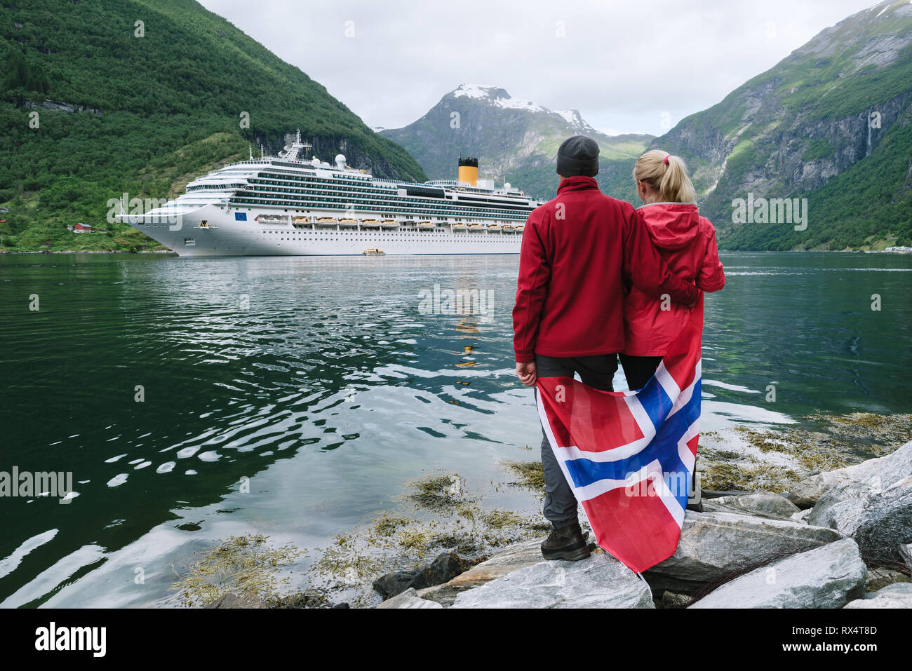 Croisière en mer de Norvège. Couple de voyageurs avec un drapeau norvégien regardez la croisière. Près de la ville de Geiranger Fjord Geirangerfjord Banque D'Images