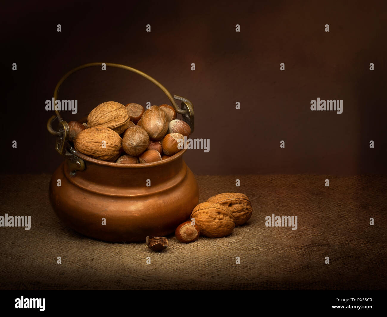 Hazel pécan et amandes - noix dans un bol en cuivre. Lumière de clair-obscur de la peinture. Vintage style de vie encore. Banque D'Images