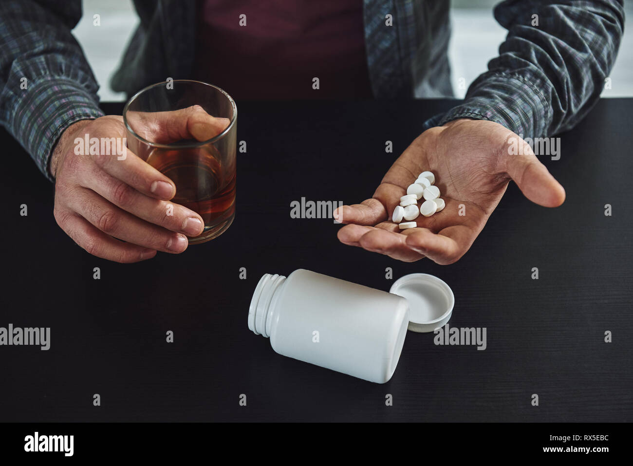 Portrait of male hands holding jar une pilule et un verre de whisky sur le  tableau noir. La souffrance de l'homme dans la gueule de l'alcoolisme et  l'abus d'alcool. Une bott Photo