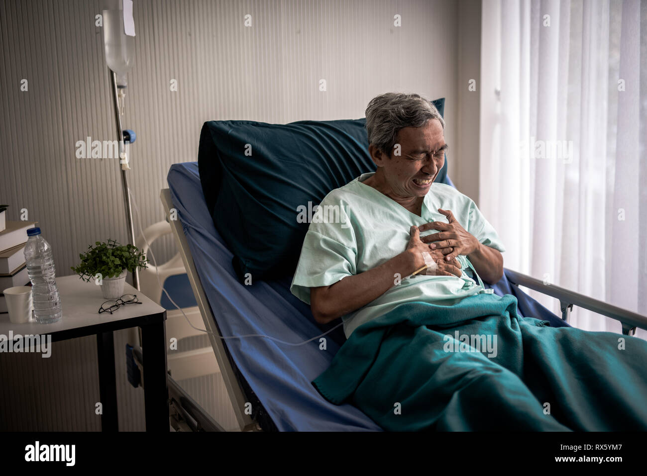 Homme mature avec douleur à la poitrine qui souffrent de crise cardiaque en lit d'hôpital. Banque D'Images