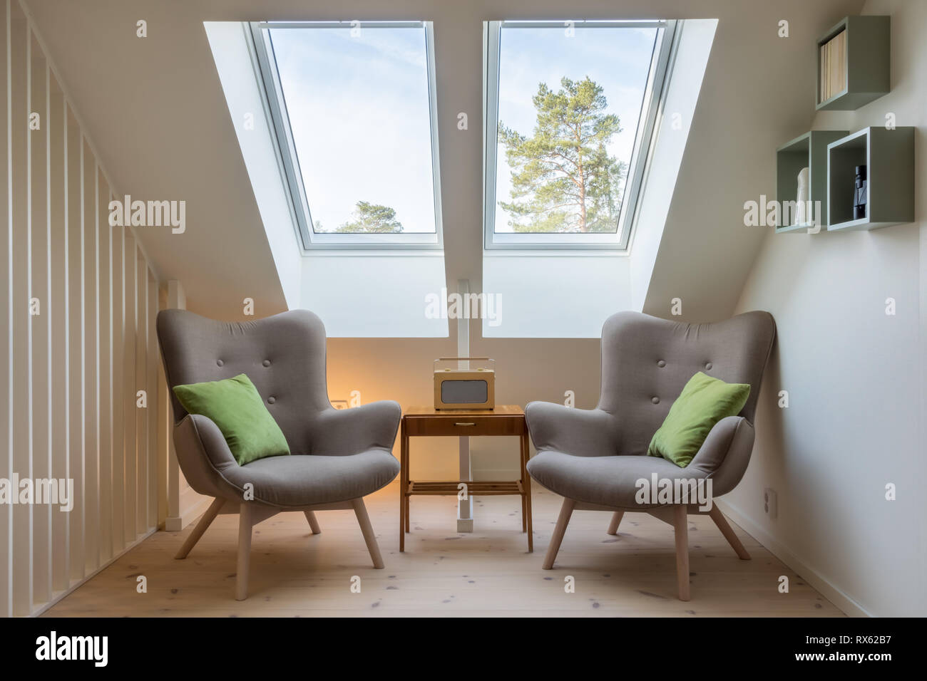 Design rétro moderne dans un grenier/loft. Petite table d'époque avec une radio et deux fauteuils de lecture dans deux puits de lumière. Banque D'Images