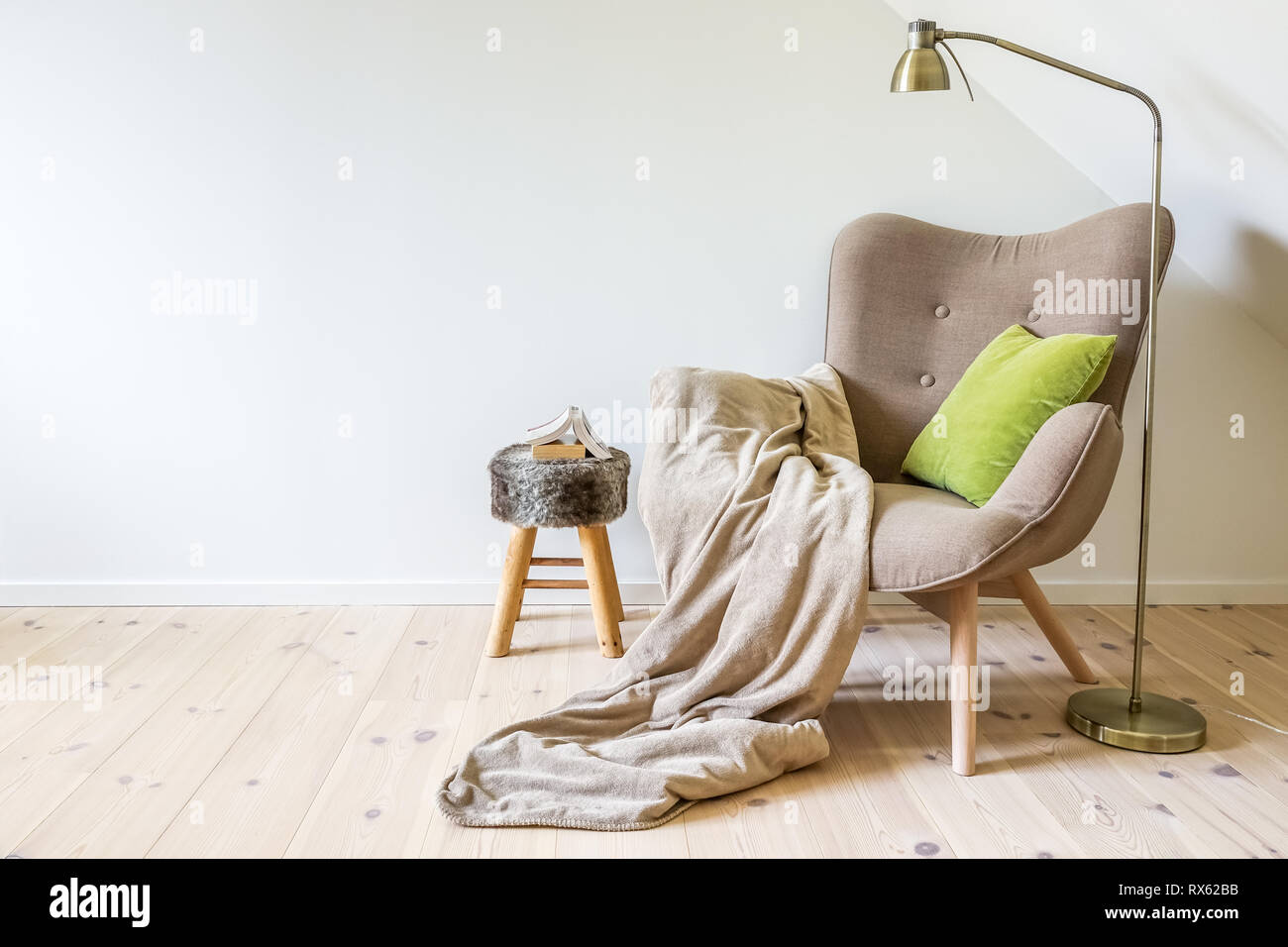Une chaise de lecture / fauteuil avec une lampe, une couverture et un livre ouvert. Mur blanc vide à l'intérieur salon simple. Copy space Banque D'Images