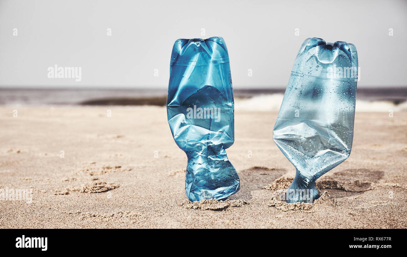 Deux bouteilles en plastique bloqué dans le sable sur une plage, selective focus, harmonisation des couleurs appliquées. Banque D'Images