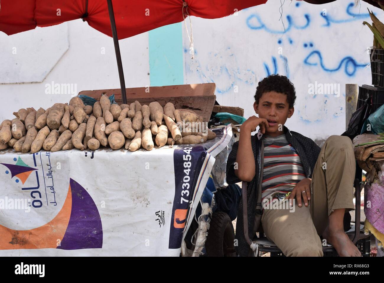 D'Aden, au Yémen. Mar 8, 2019. Un enfant est assis à côté d'un stand du vendeur dans une rue d'Aden, au Yémen, le 8 mars 2019. Des milliers de jeunes Yéménites ont été poussées dans les rues à la suite d'un conflit militaire croissante qui a éclaté entre les forces du gouvernement du Yémen et les rebelles Houthi en 2015. Le nombre d'enfants des rues continue d'augmenter sur une base quotidienne que les combats se poursuivent, l'expansion pour inclure un plus grand nombre de provinces dans le pays arabe au milieu de l'absence de solutions politiques à la fin de quatre ans de guerre civile. Credit : Murad Abdo/Xinhua/Alamy Live News Banque D'Images