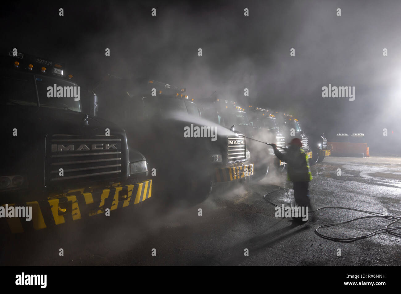Construction à projection travailleur de camions à benne très tôt le matin Banque D'Images