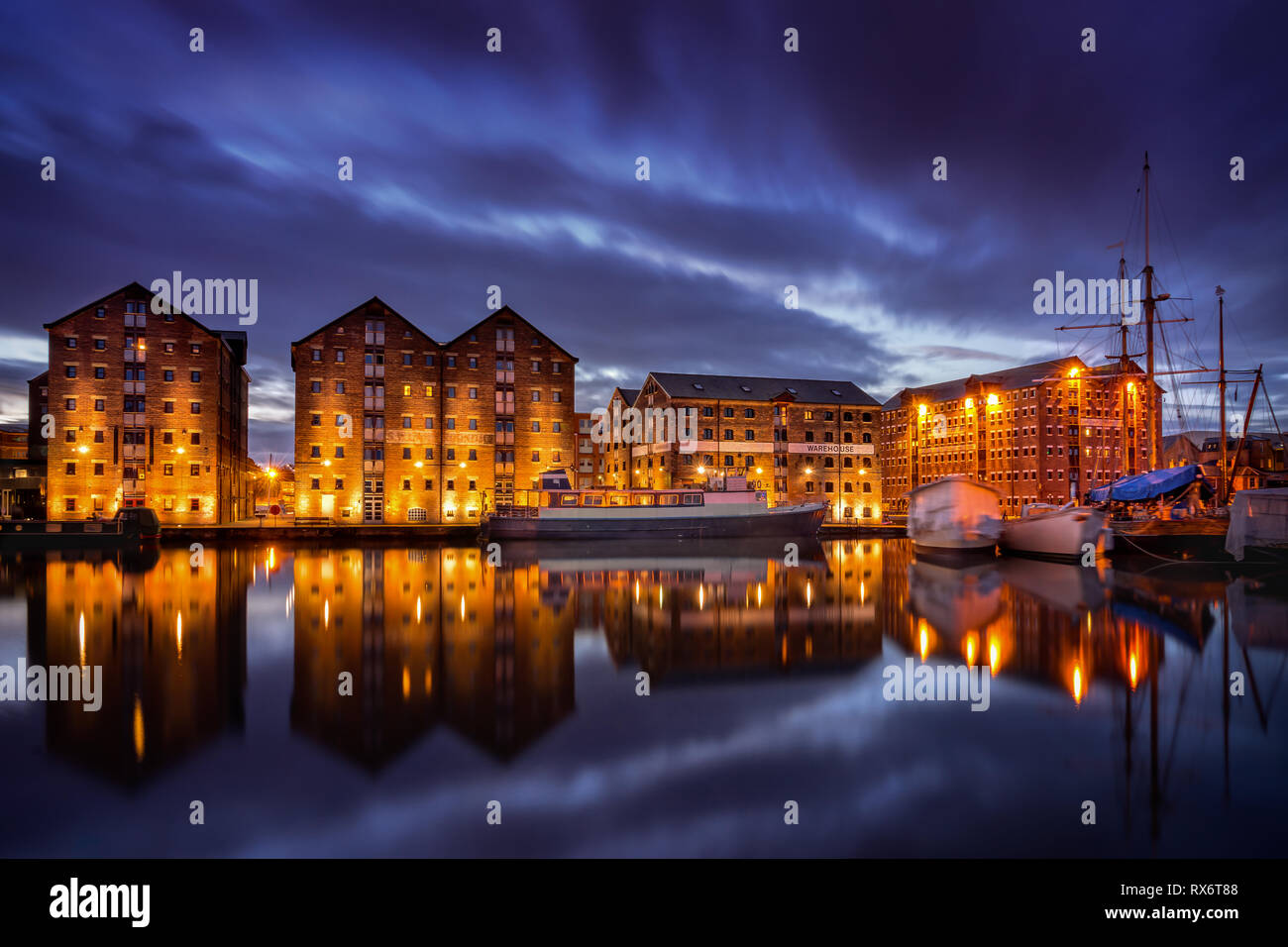 Gloucester Docks de nuit avec la réflexion d'entrepôts et des bateaux sur le canal de la netteté Banque D'Images