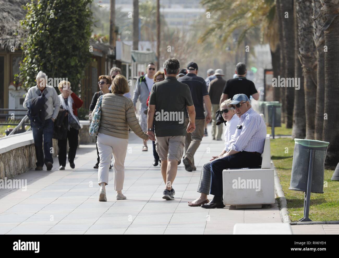 Les touristes passent devant un couple de personnes âgées assis sur une banque à Torremolinos, Espagne, 13. Février 2019. L'économie espagnole est en attente de voir comment la Grande-Bretagne du futur départ de l'Union européenne pourrait s'appliquer à l'Espagne. Dans le monde d'utilisation | Banque D'Images
