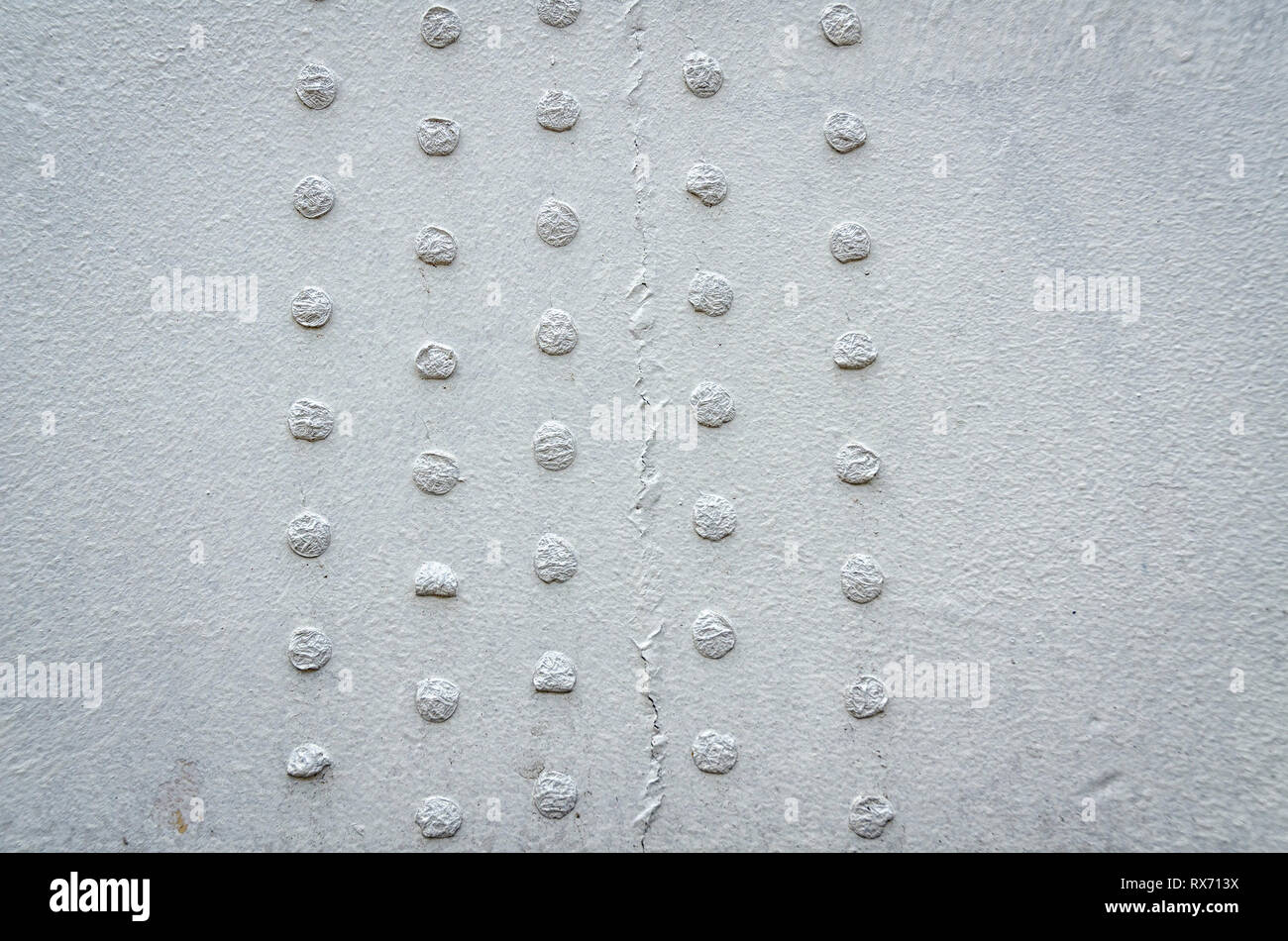 Un gros plan d'un mur gris sale avec des petits cercles. Banque D'Images