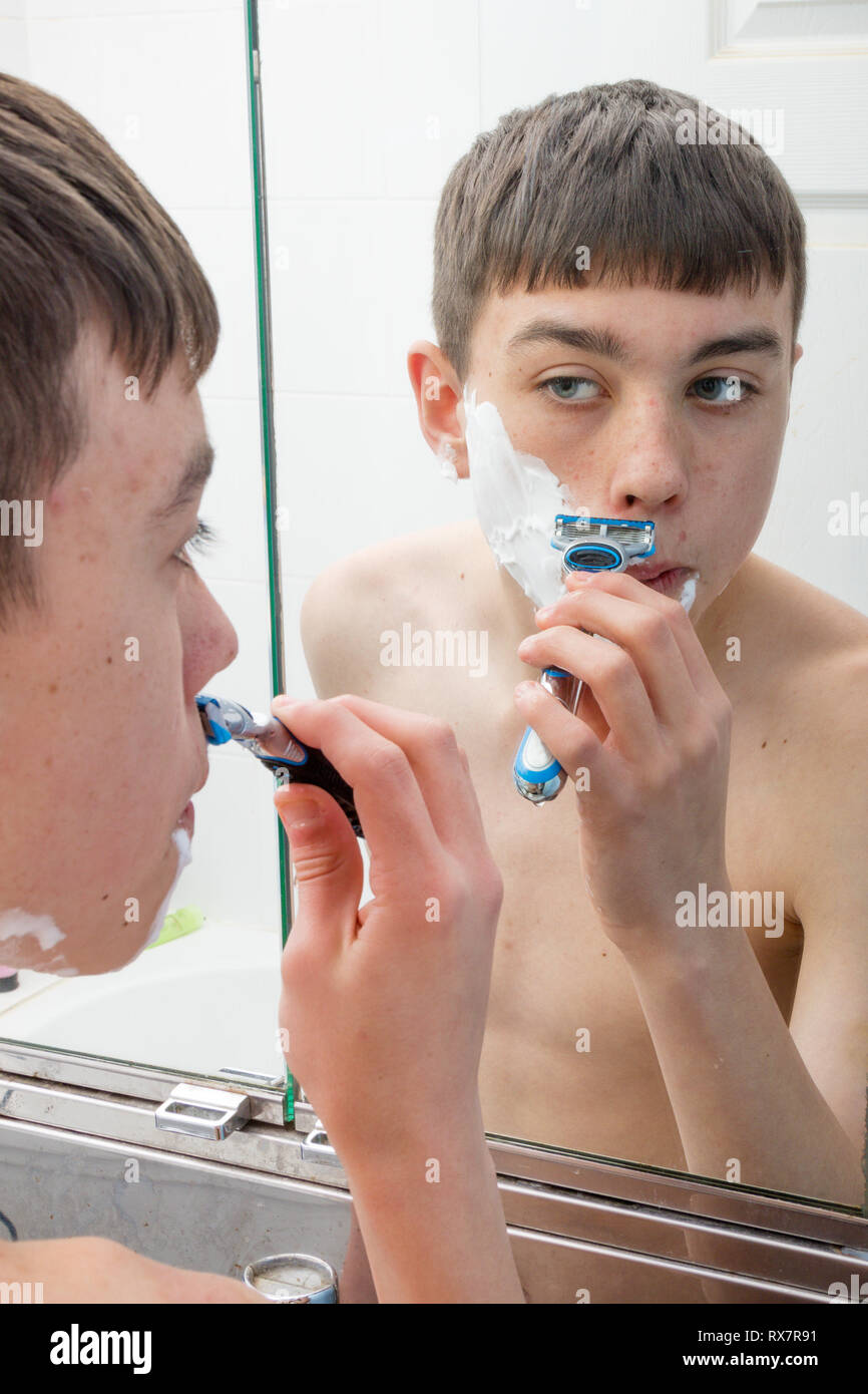 Adolescent à l'aide d'un miroir pour se raser le matin Photo Stock - Alamy