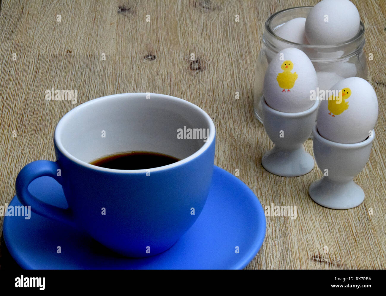 Grande tasse de café et des œufs de pâques avec le poulet peint sur eux et les oeufs dans un bocal de verre sur fond de bois Banque D'Images