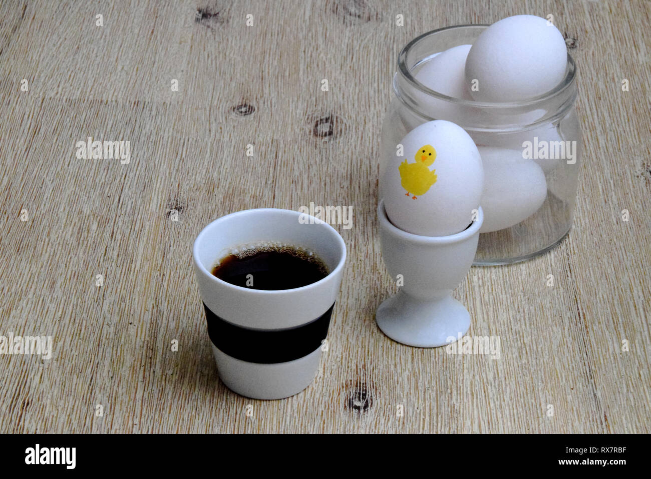 Du café et des œufs à la coque pour le petit déjeuner de Pâques sur table en bois avec des oeufs dans un bocal en verre à l'arrière-plan Banque D'Images