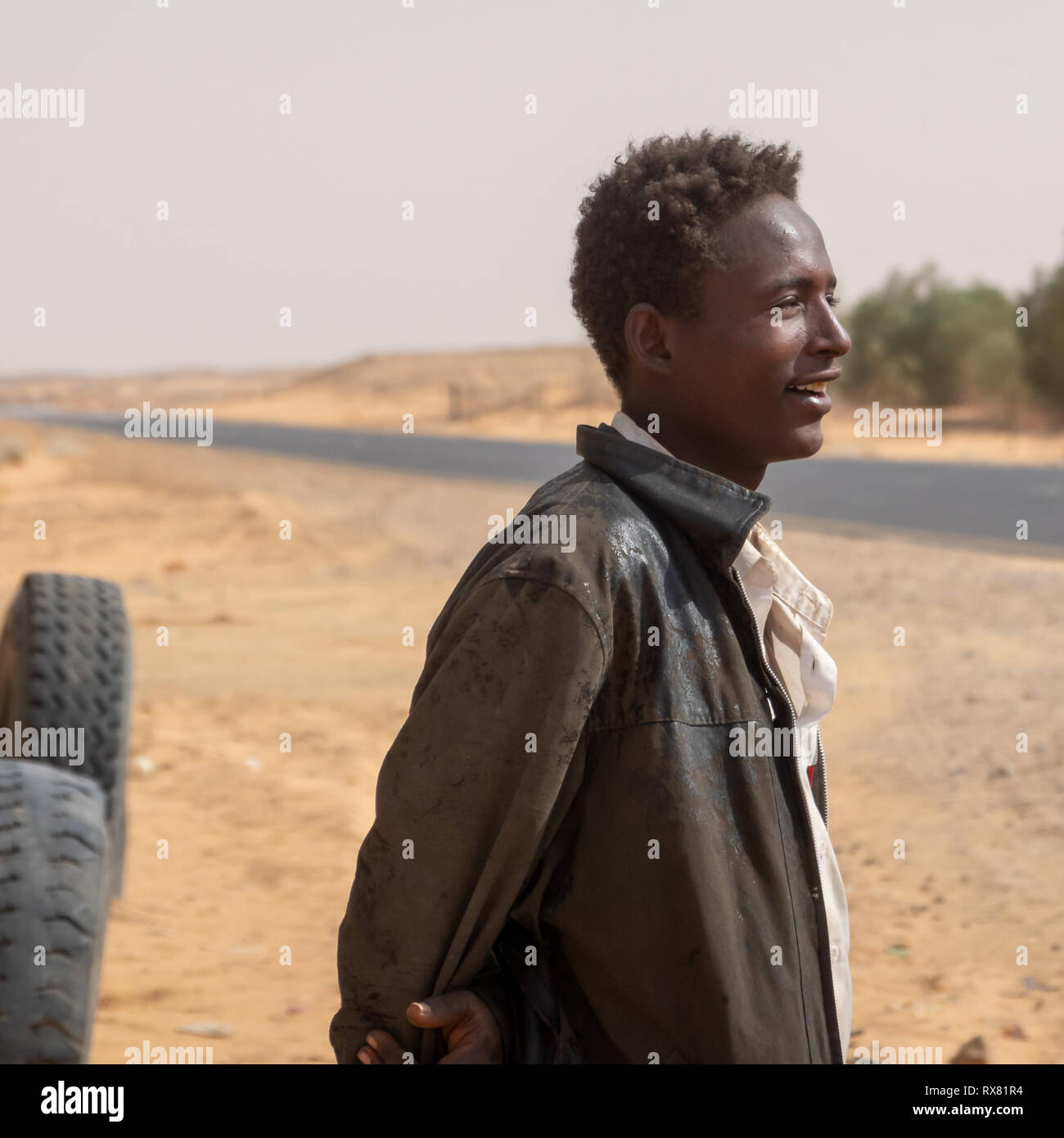 Kerma, au Soudan, le 8 février, 2019. : Jeune homme souriant soudanais en portrait sur la route à travers le désert dans le nord du Soudan avec de vieux cuir usé jmd Banque D'Images