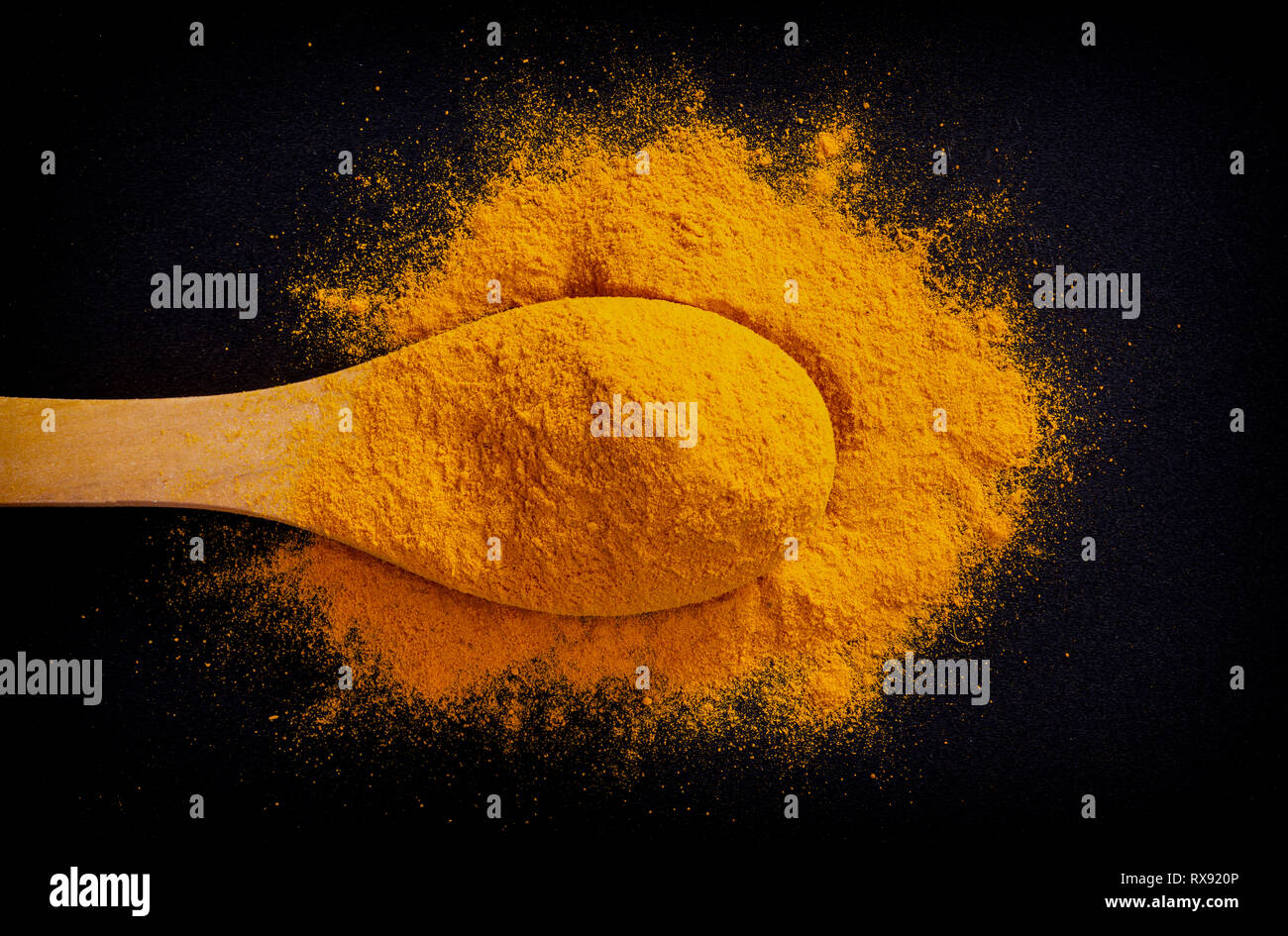 Des tas d'épices curcuma curcuma sur cuillère en bois sombre sur fond noir, vue du dessus Banque D'Images