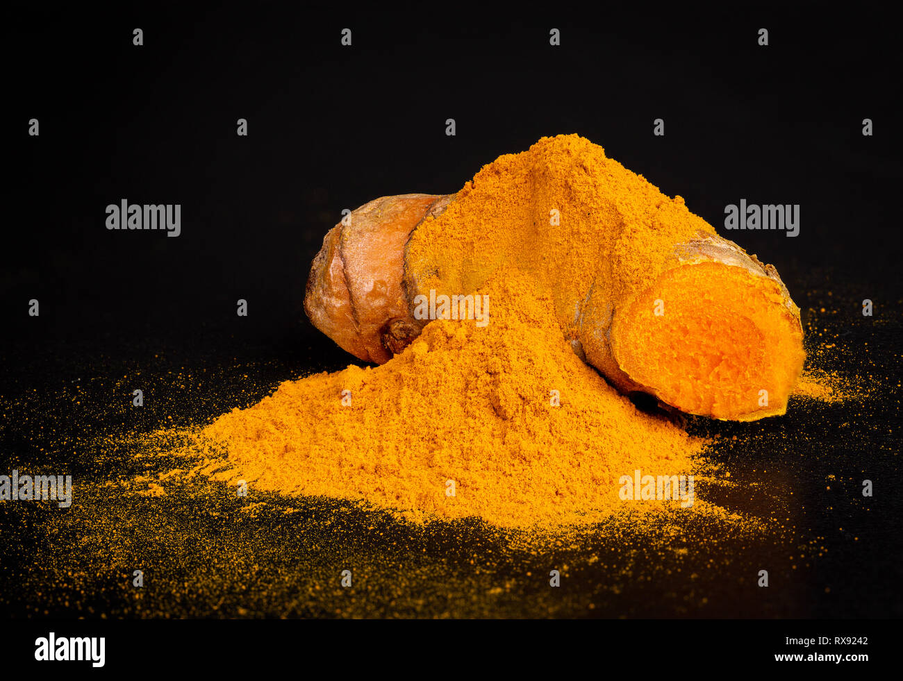 Des tas d'épices curcuma curcuma avec racines sur fond noir foncé Banque D'Images