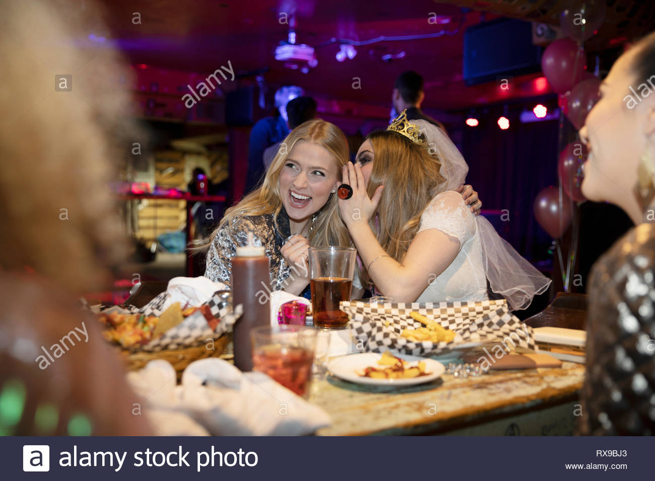 Chuchotant à l'oreille de bachelorette ami à diner de fin de nuit Banque D'Images