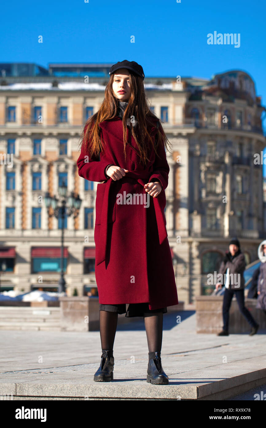Portrait complet du corps. Belle jeune femme brune en élégant dans un long manteau  bourgogne walking in spring street Photo Stock - Alamy