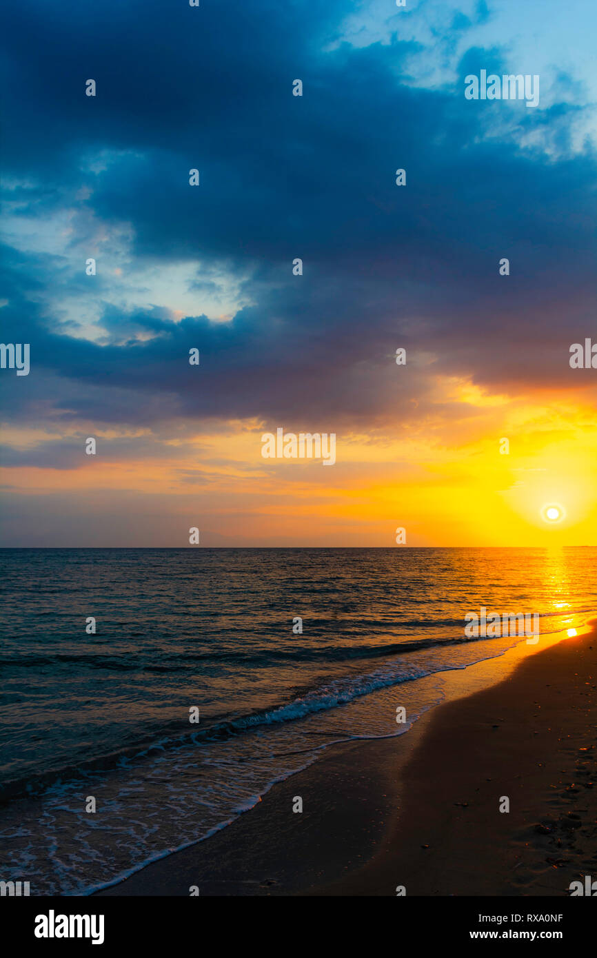 Côte de soleil vertical mer calme avec soleil et nuages d'or - Fin de l'après-midi sur la plage de flottaison avec coucher du soleil calme mer océan ciel dramatique nuages nuage Banque D'Images