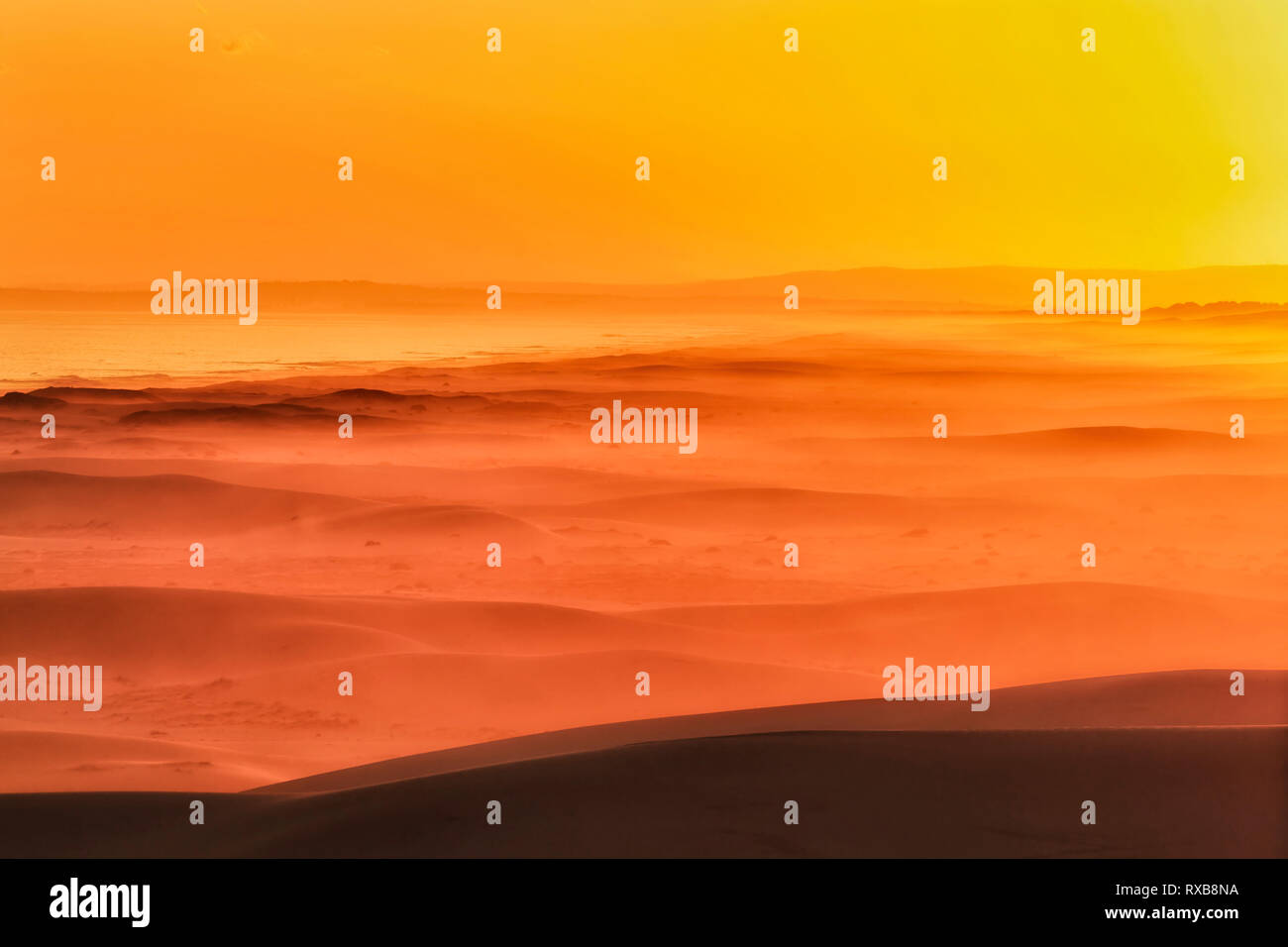 Orange et jaune chaud lumière du soleil au coucher du soleil plus de Stockton Beach côte pacifique de l'Australie sur les vagues de dunes de sable. Banque D'Images