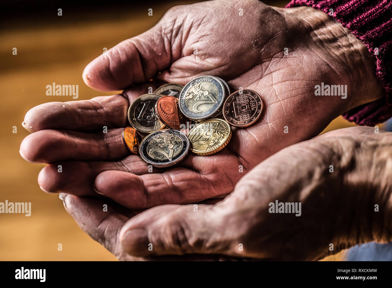 Pensionné homme tenant en mains les pièces en euros. Thème de retraites faibles Banque D'Images