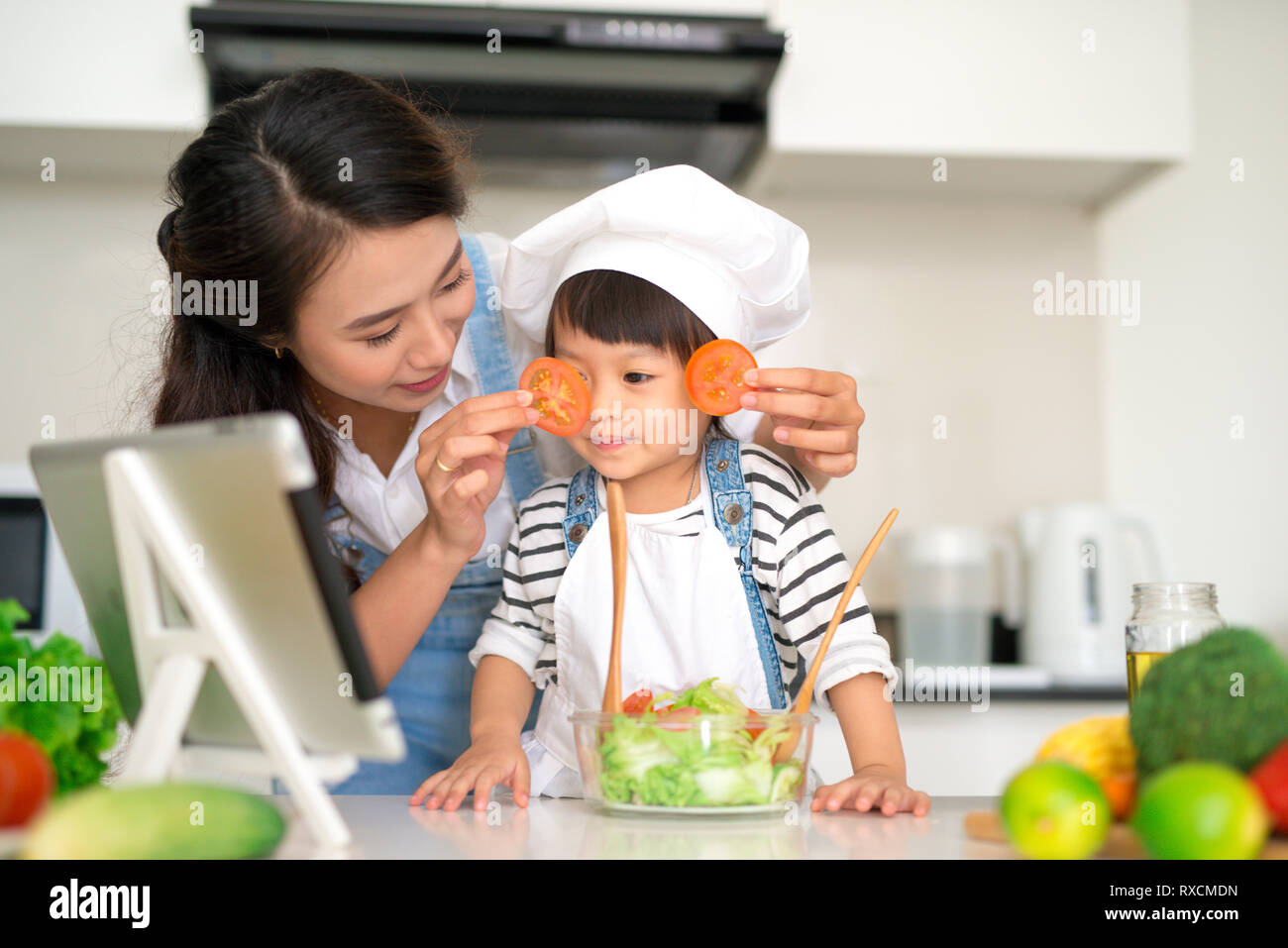 Famille heureuse dans la cuisine. Mère et enfant fille sont en train de préparer les légumes et les fruits. Banque D'Images