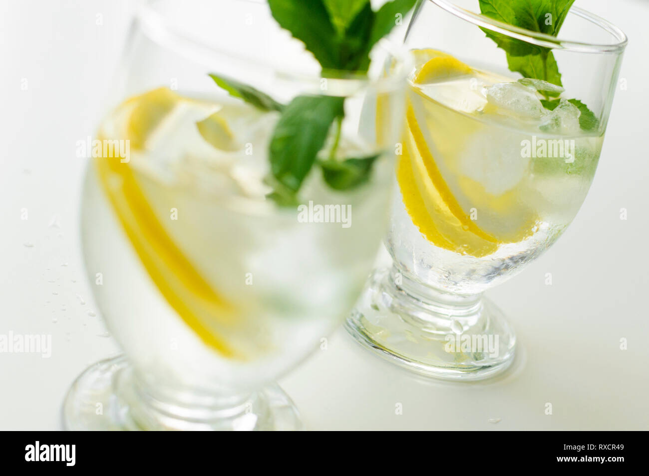 Deux verres transparents avec limonade rafraîchissante et froid avec des glaçons, tranches de citron et feuilles de menthe. Banque D'Images