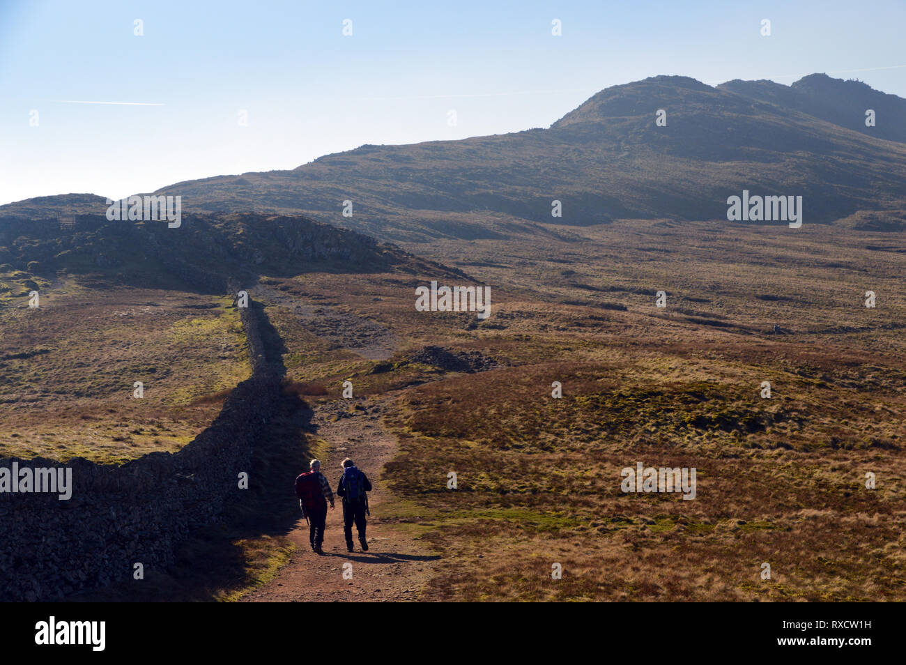 Deux randonneurs à pied de l'Birkhouse Wainwright Moor à bord de route à Helvellyn marchant dans le Parc National du Lake District, Cumbria, Angleterre. Banque D'Images