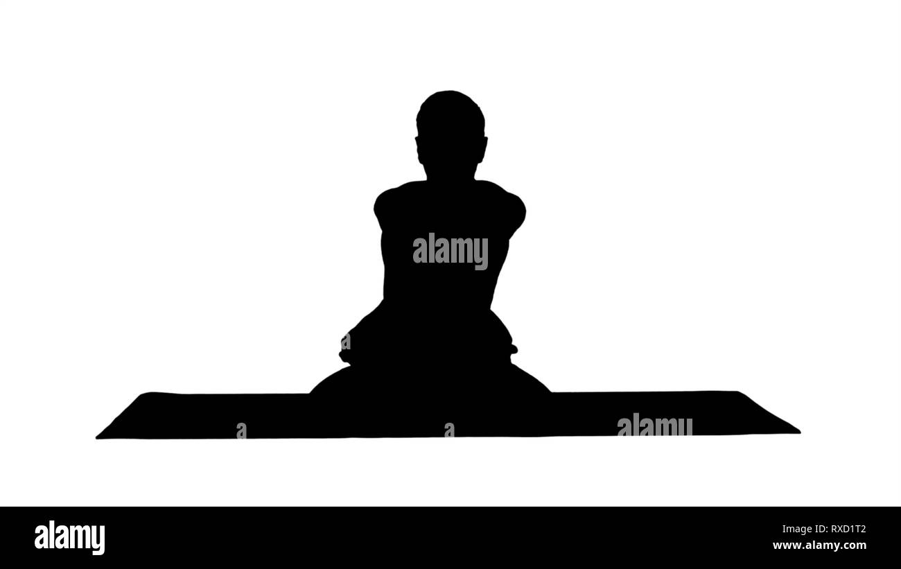 Silhouette beau jeune homme sportif pratiquant le yoga, assis en tailleur dans Adho Mukha le Padmasana, flexion de l'avant dans la variation de Lotus. Banque D'Images