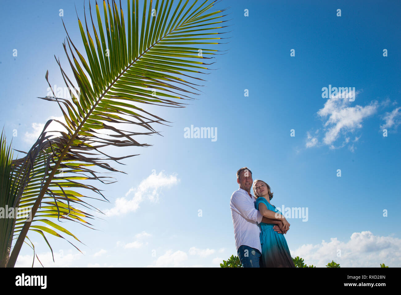 Couple hugging in Mexico. Branche de palmier au premier plan et man hugging son épouse ou petite amie du derrière. Photo du rétroéclairage Banque D'Images