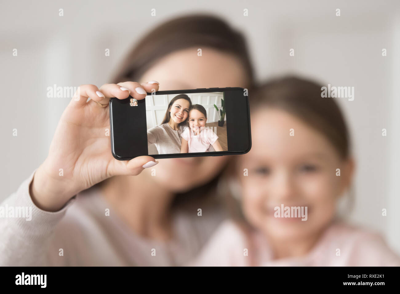 Happy mother holding phone prendre on cellphone selfies avec fille Banque D'Images