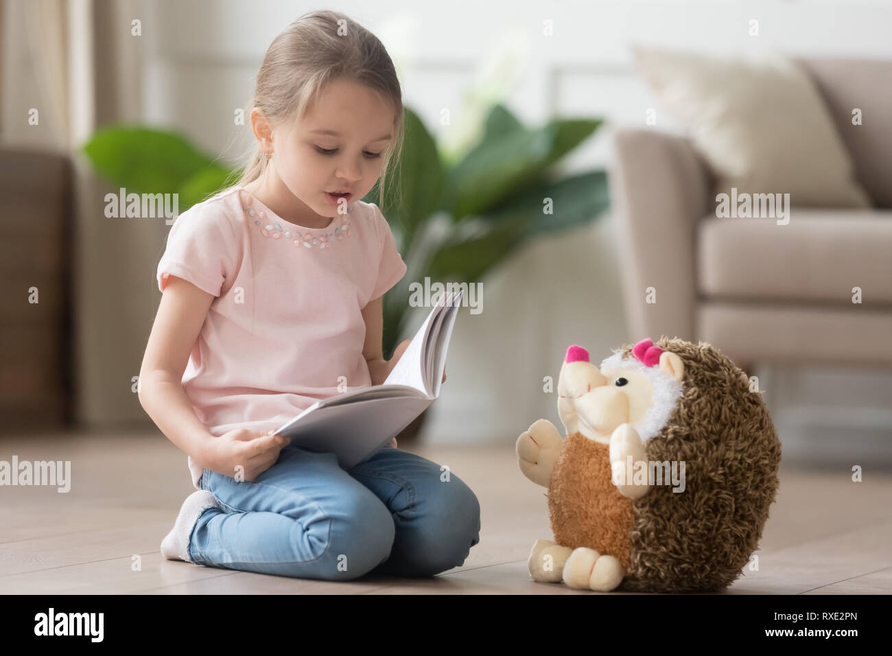 Cute little kid girl jouer seul lecture livre à toy Banque D'Images