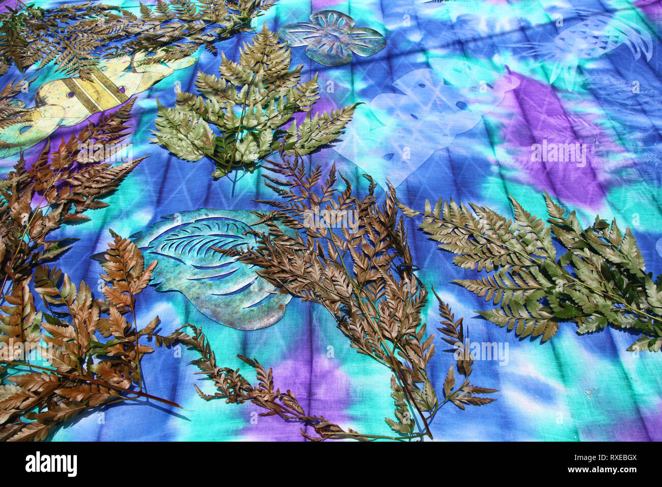 Tissu coloré avec des feuilles, des fougères et des formes de papier découpées demonstraiting comment créer tie dye designs, Bora Bora, Polynésie française. Banque D'Images