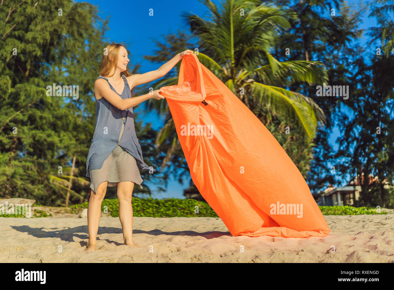 Portrait de femme de style de vie d'été se gonfle un canapé orange gonflable sur la plage de l'île tropicale. Se détendre et profiter de la vie sur un lit d'air. Banque D'Images