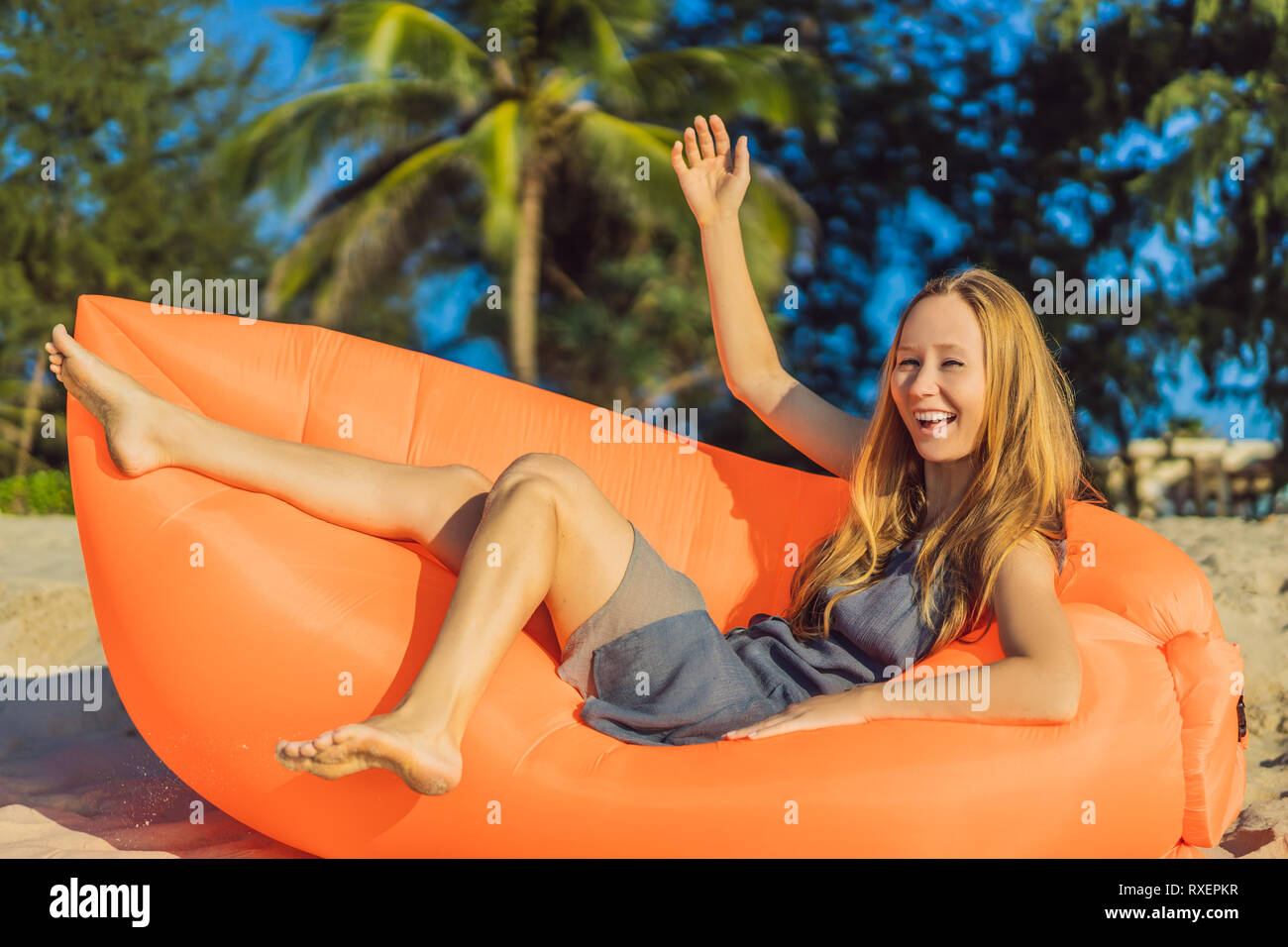 Portrait de vie d'été jolie fille assise sur le canapé gonflable orange sur  la plage de l'île tropicale. Se détendre et profiter de la vie sur un lit  d'air Photo Stock -