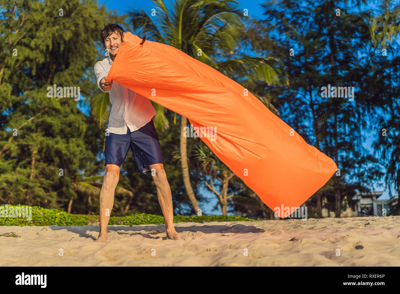 Vie de l'homme portrait d'été se gonfle un canapé orange gonflable sur la plage de l'île tropicale. Se détendre et profiter de la vie sur un lit d'air. Banque D'Images