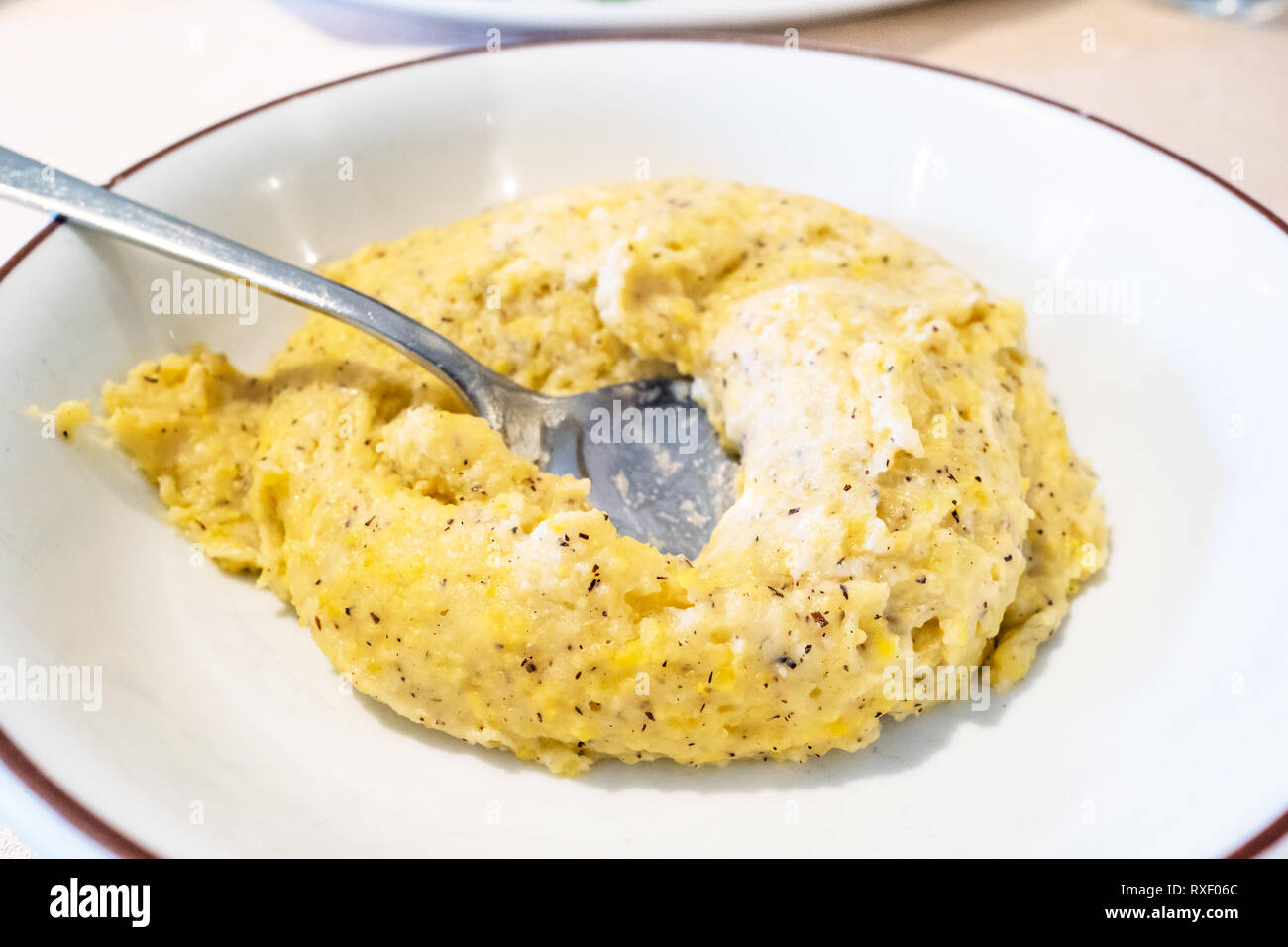 Cuisine italienne - portion de polenta Taragna (porridge à partir d'un mélange de maïs et de farine de sarrasin avec du beurre et fromage) sur plaque blanche dans les reste Banque D'Images