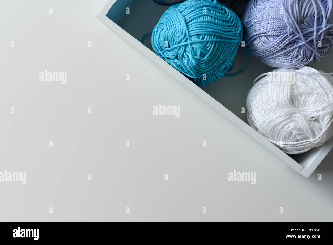 Florale de blanc, bleu et violet laines à tricoter dans une case blanche dans le coin de l'image avec l'espace de copie. Banque D'Images