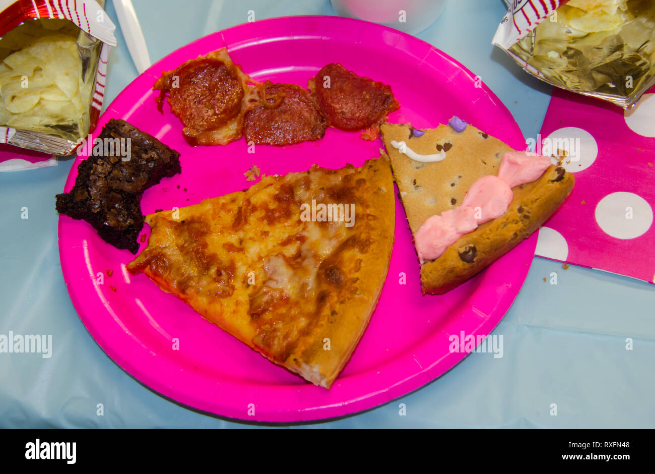 Anniversaire de la nourriture avec un morceau pris dans un assortiment de gâteries dont des pizzas, chips, gâteaux et biscuits brownies. Banque D'Images