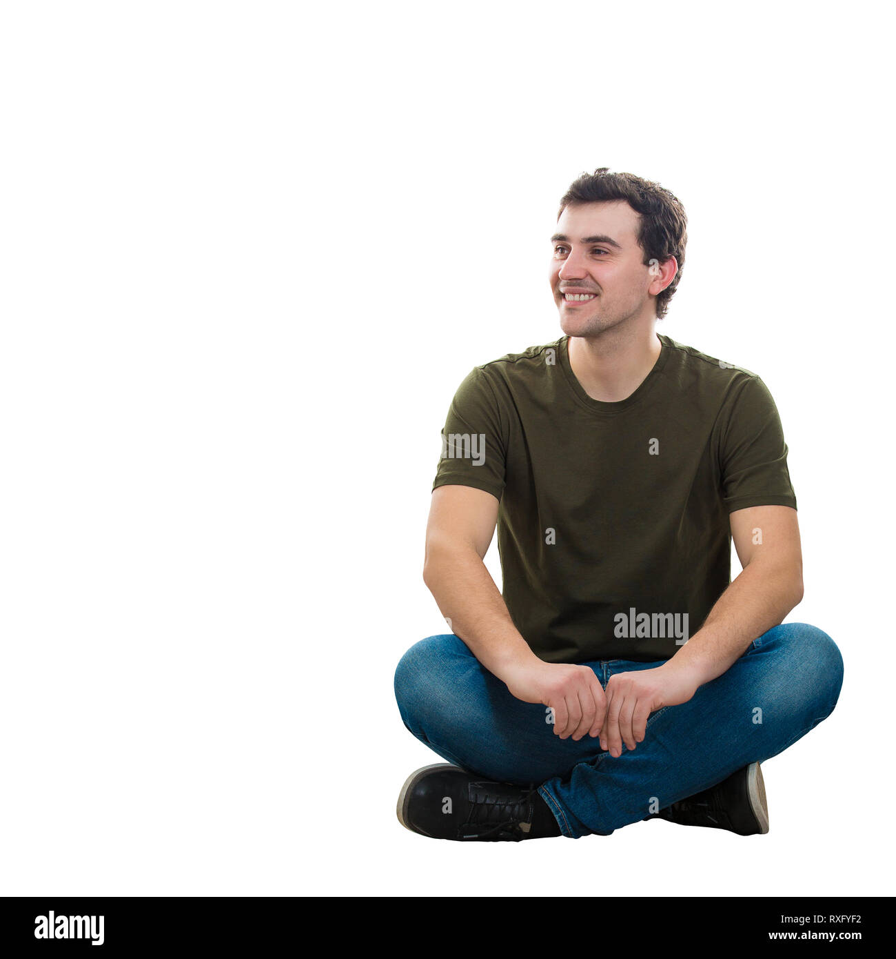 Handsome young man wearing jean décontracté et t-shirt, assis sur le sol les jambes croisées détendue, détournant les smiling isolated over white bac Banque D'Images