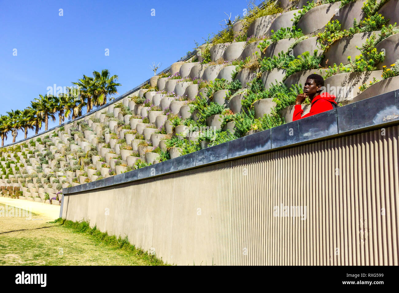 Valencia Central Park Russafa district un homme afro-américain en vêtements rouges regarde l'espace, Espagne Europe Banque D'Images