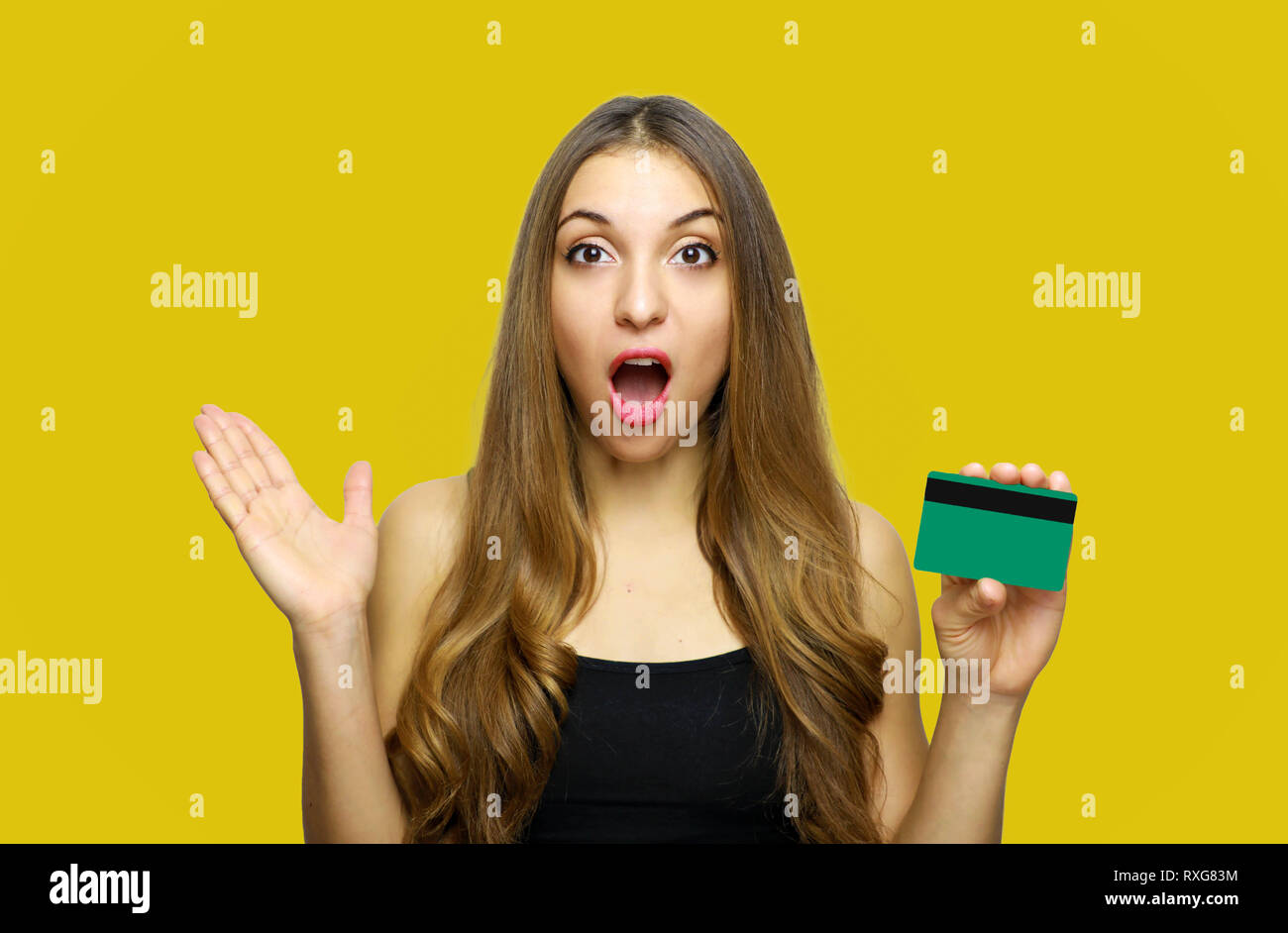 Portrait of happy young woman holding étonné surpris carte de crédit sur fond jaune Banque D'Images